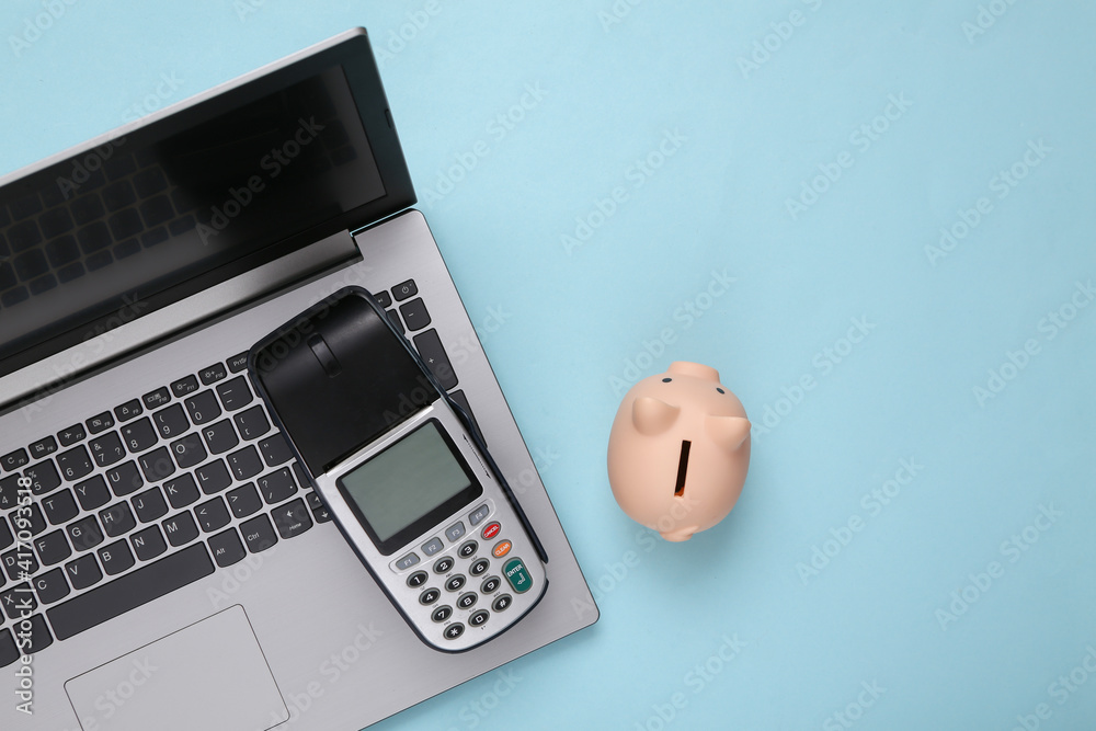 Payment terminal with piggy bank and laptop on blue background. Payment for purchases. Online shopping. Top view Payment terminal with piggy bank and laptop on blue background. Payment for purchases. Online shopping. Top view