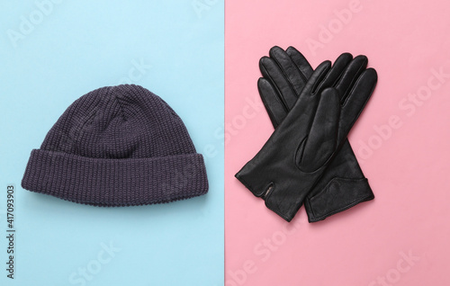 Stylish beanie hat and gloves on blue pink pastel background