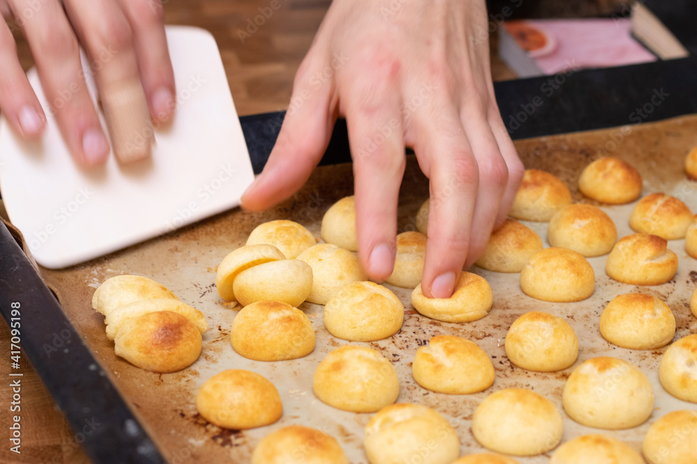 Hands holding pan de queijo, a Brazilian mini cheese bread finger food, party food and snack