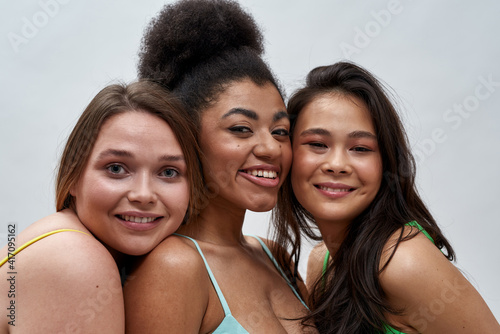 Portrait of diverse young women with different body shapes wearing underwear smiling at camera, posing together isolated over light background