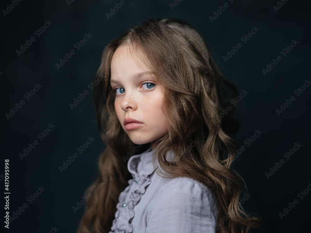 portrait of a beautiful girl in a gray dress on a dark background and curly hair blue eyes portrait of a beautiful girl in a gray dress on a dark background and curly hair blue eyes