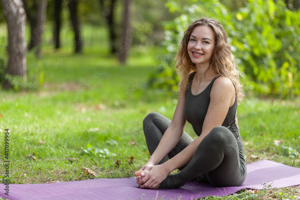 Happy Caucasian yogi woman sitting on a mat on the grass. Healthy lifestyle Happy Caucasian yogi woman sitting on a mat on the grass. Healthy lifestyle
