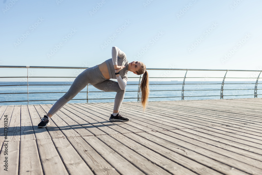 Young fit woman in sportswear practices yoga asana pose on the beach on a bright sunny day. Young fit woman in sportswear practices yoga asana pose on the beach on a bright sunny day.