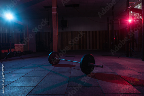Barbell in a dark grungy gym with blue red neon light