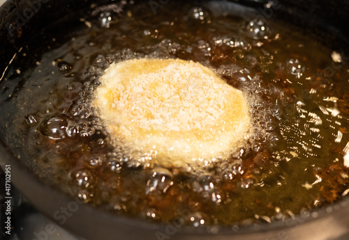 Frying chicken nuggets in oil on a frying pan