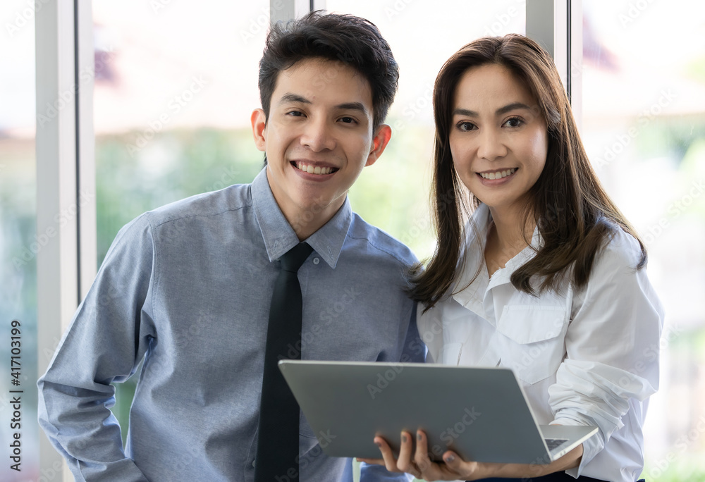 Beautiful black long hair Asian businesswoman standing and holding laptop notebook and looking to camera Beautiful black long hair Asian businesswoman standing and holding laptop notebook and looking to camera