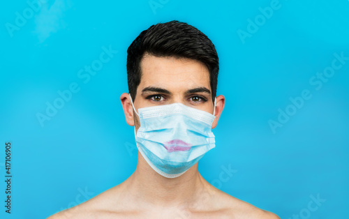 Obraz na plátne Young made-up man with face mask on a blue background