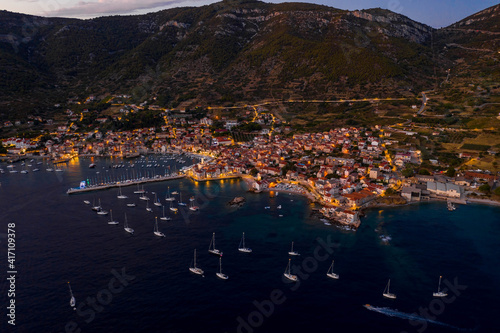 Aerial drone shot of Komiza town port in night with city light on Vis Island in Croatia summer dusk
