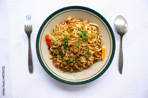 Mie Goreng Jawa or bakmi jawa or java noodle with
spoon and fork. Indonesian traditional street food noodles from central java or Yogyakarta, indonesia on white background. photo
