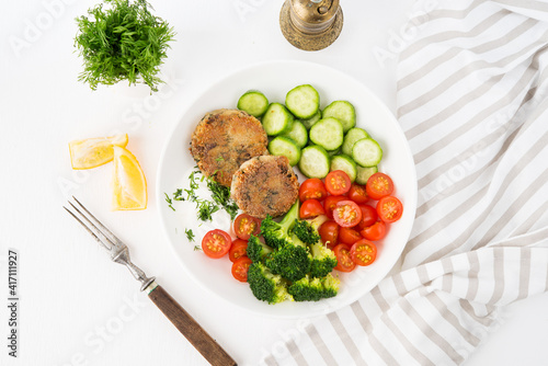 Vegetarian dish of potato patties with herbs and vegetables in a plate