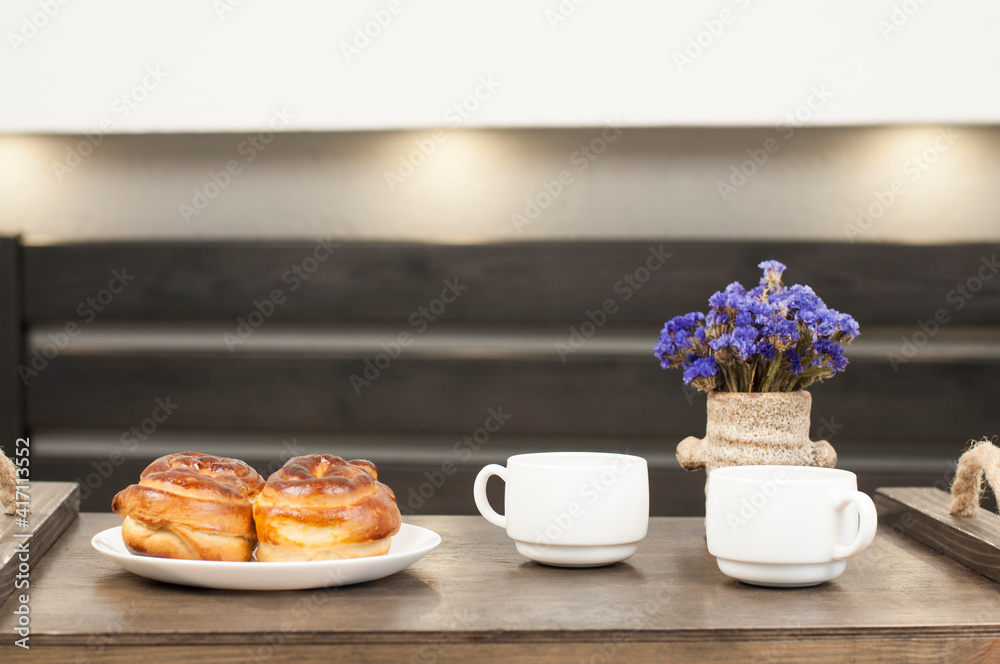 Two cups of coffee on a tray. A bun and a bouquet of flowers. Breakfast in bed.