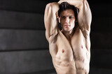 Handsome strong male fitness model close up posing over dark background.