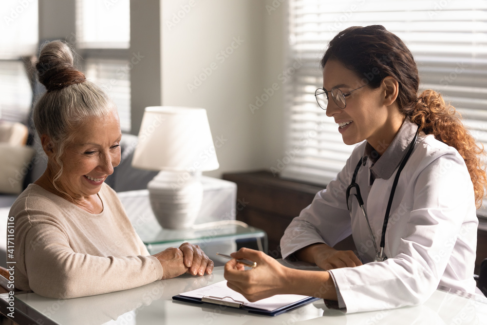 Close up smiling female doctor wearing glasses and uniform consulting mature woman patient about contract, insurance agreement at meeting in hospital office, explaining treatment, checkup results Close up smiling female doctor wearing glasses and uniform consulting mature woman patient about contract, insurance agreement at meeting in hospital office, explaining treatment, checkup results