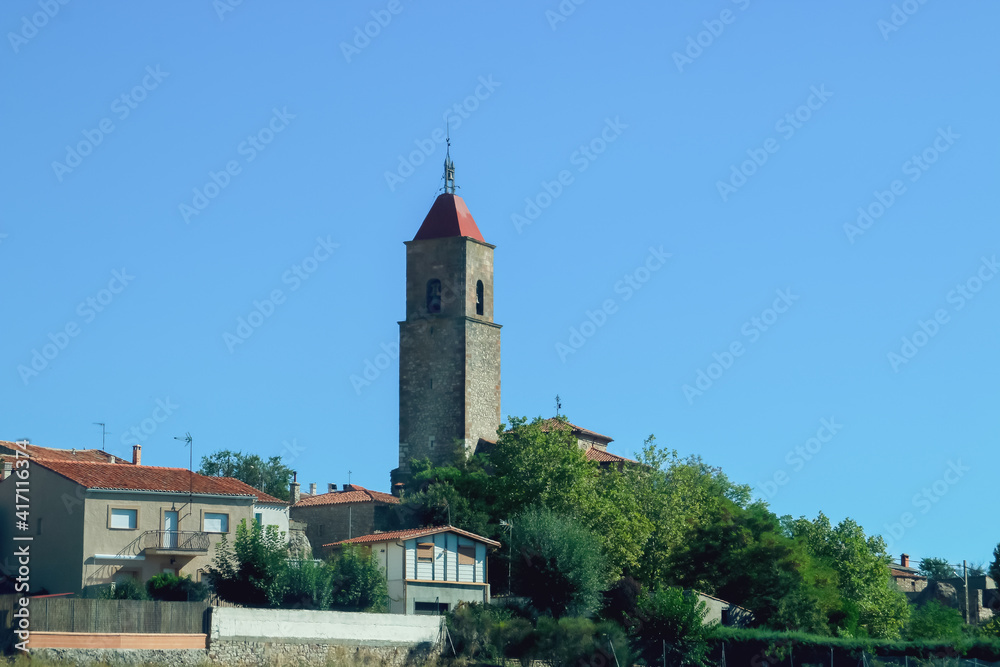 Campanario de la Iglesia de Nuestra Señora del Rosario del pueblo Alcolea del Pinar. Campanario que sobresale por encima del resto de tejados de las casas de la localidad. Soria, España.