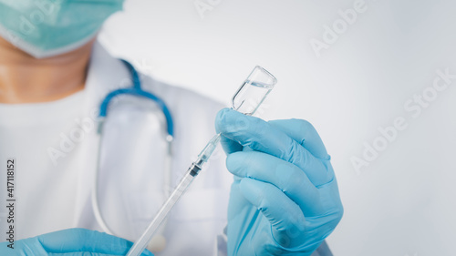 Doctor wear hand in blue gloves holding a syringe with liquid vaccines,Concept fight against virus covid-19 corona virus.