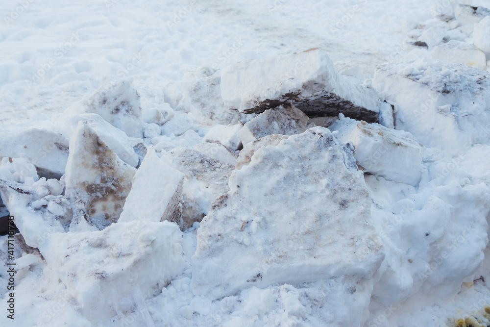 Closeup of large chunks of dirty snow, from a snowplow, on the street. Chunks of dirty snow on the side of the road