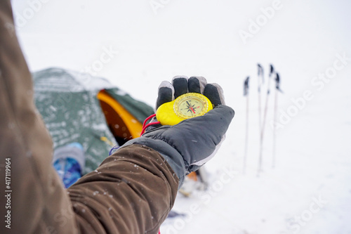 Big beautiful yellow compass in hand. A traveler holds a gloved compass at the north pole in winter. Compass on a winter expedition