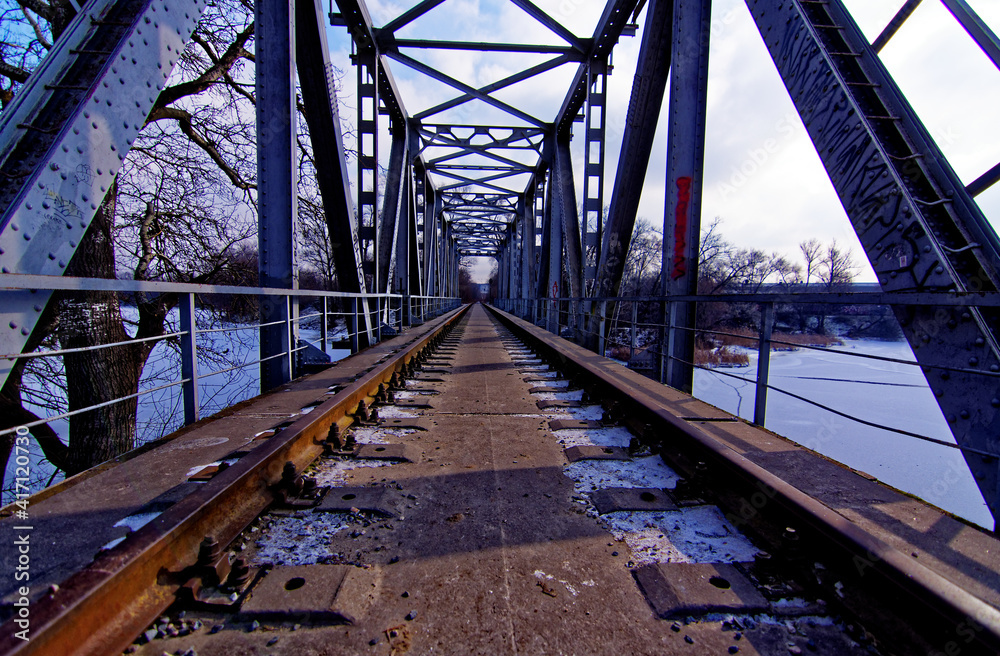 an abandoned railway bridge over a frozen river