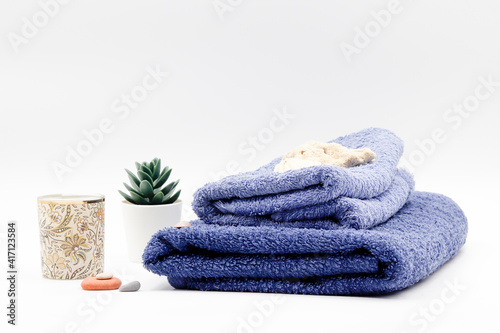 set consisting of blue towel with candle plant and stones.