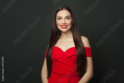 Happy brunette woman with long healthy straight hair smiling on black background