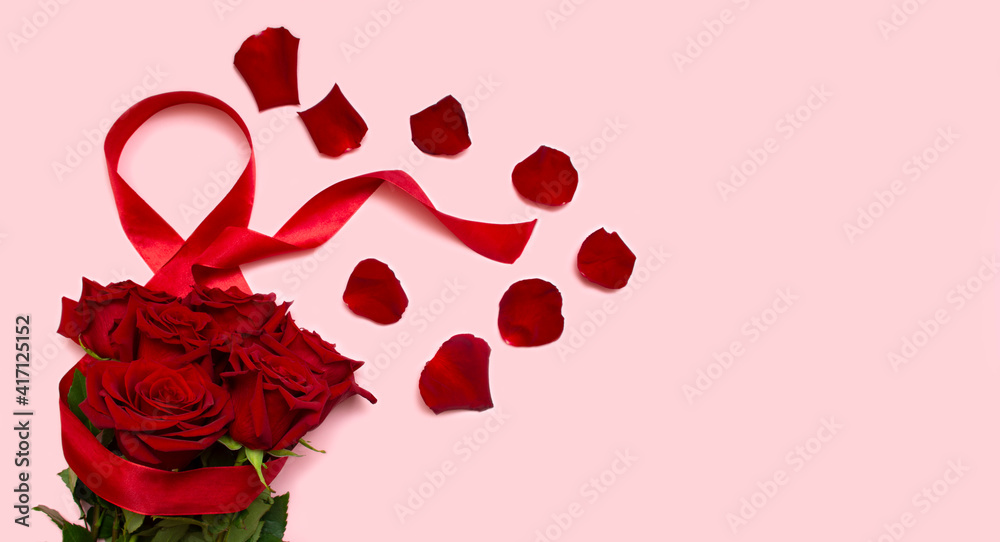 March 8, the concept of the international Women's Day holiday, Red roses on a pink background with a red ribbon and rose petals, a blank for a postcard, a place for the text