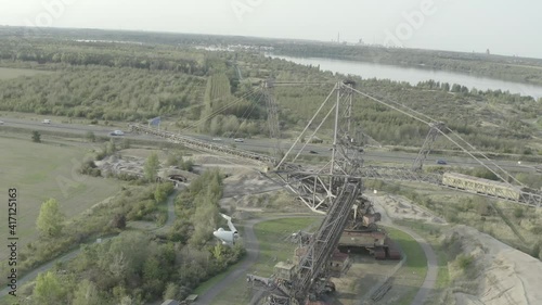 Aerial drone shot of a profitable open cast mining site with an industrial bucket wheel excavator next to a highway with driving cars passing by in Germany photo