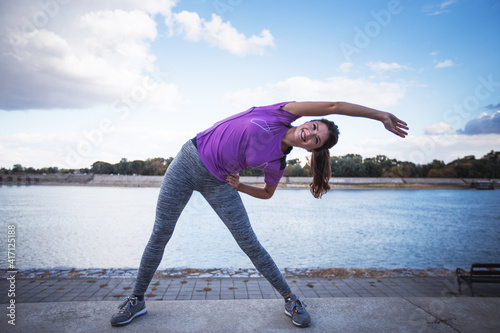 Fitness woman doing exercise outdoor near river