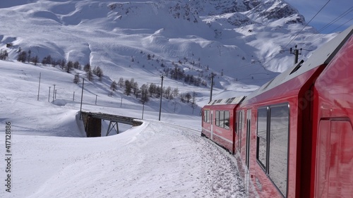 Europe, Switzerland Alps , Poschiavo February 2021 - Live shot from the window of the Bernina Express, red train pass in Ospizio Bernina station - White lake ( lago bianco ) frozen 