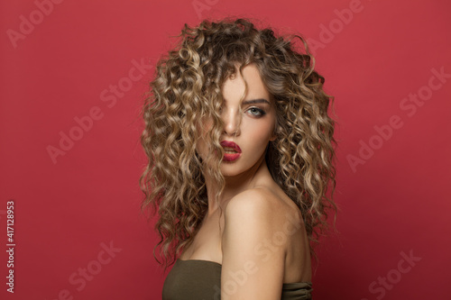 Perfect young woman model with curly hairstyle on red background