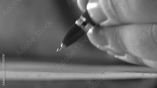 writes with an old pen on paper. close-up. black and white. Senior man writing down letters on a piece of paper. Close up of Old male hands writing