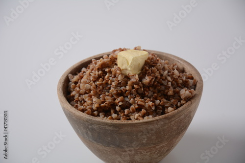 Bowl of tasty buckwheat porridge with piece of butter on the top