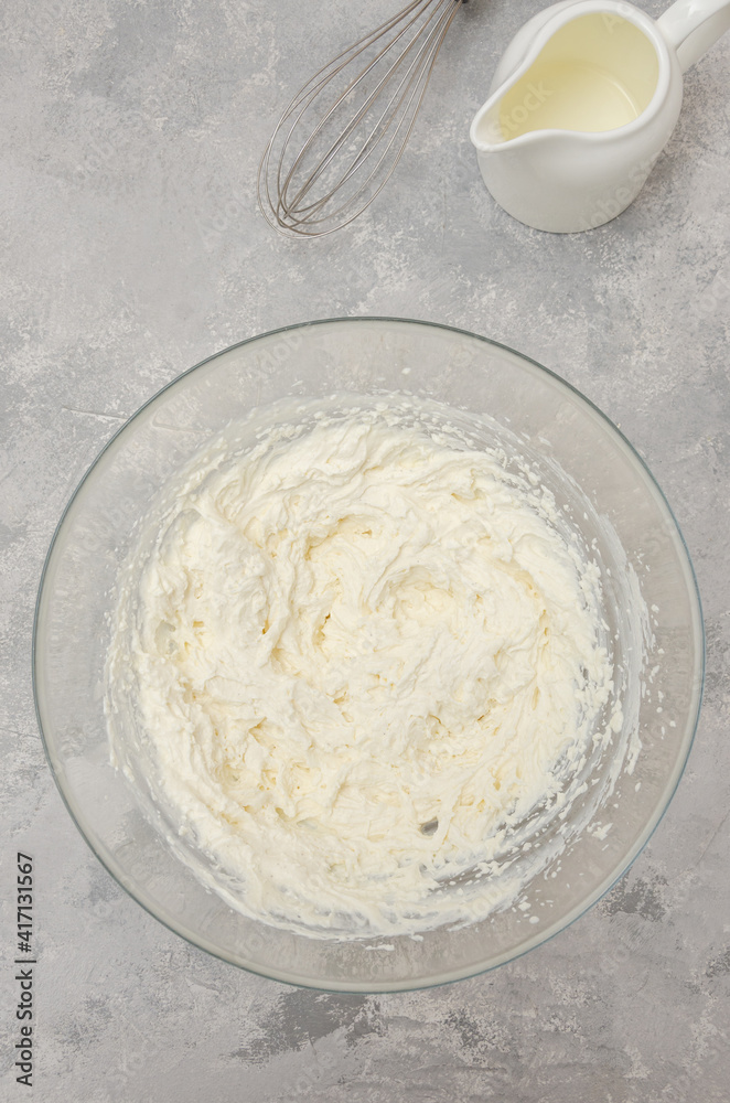 Ready cream of cream cheese in a bowl to make the cake on a gray concrete background. Top view.