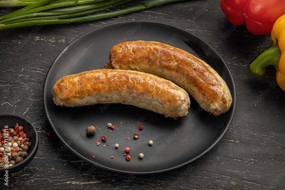 Fried sausages in a black plate on a wooden table