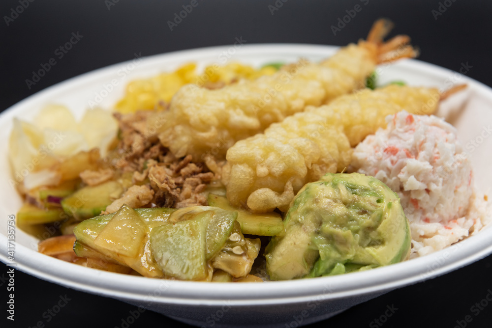 Small bowl of poke topped with shrimp tempura, crab meat, edemame, and corn served up and ready to eat. Small bowl of poke topped with shrimp tempura, crab meat, edemame, and corn served up and ready to eat.