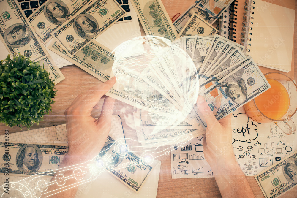 Double exposure of world map drawing hologram and us dollars bills and man hands. Double exposure of world map drawing hologram and us dollars bills and man hands.