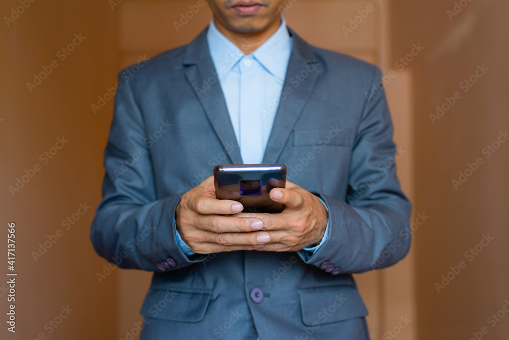 close up of business man hand using smart phone touch on screen and typing for some searching internet information technology data against gray wall background. close up of business man hand using smart phone touch on screen and typing for some searching internet information technology data against gray wall background.
