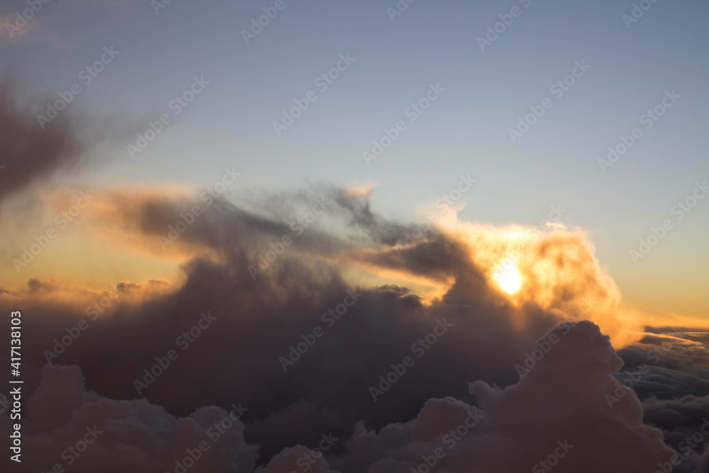 spectacular sunset seen from an airplane with clouds in the foreground and in the distance

