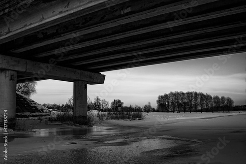 winter landscape under the bridge, highway over ice and snow covered river.