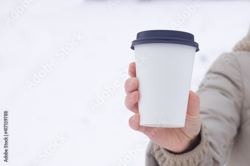Fototapeta Naklejka Na Ścianę i Meble -  Coffee to go. A paper cup in a hand with an empty space for the logo.