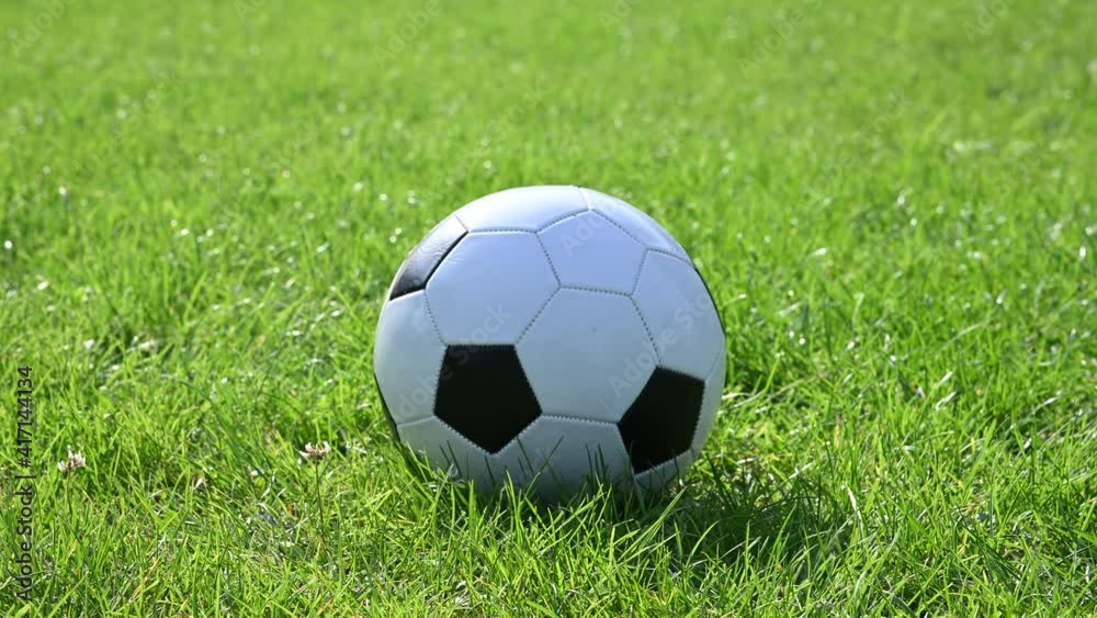 Football ball rolling on green grass field Football ball rolling on green grass field