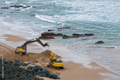 Travaux d'enrochement avec des pelleteuses sur une plage en France