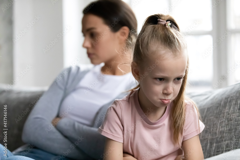 Annoyed upset quiet mother and kid sit on couch separately after arguing and quarrel. Offended school daughter girl ignoring mom. Silent parent and child going through conflict and behavior problem Annoyed upset quiet mother and kid sit on couch separately after arguing and quarrel. Offended school daughter girl ignoring mom. Silent parent and child going through conflict and behavior problem