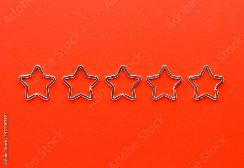 Five shiny metal split key rings in shape of star for keychains. Chromium plated keychain clasp on red background. Feedback concept. Flat lay, top view with copy space.