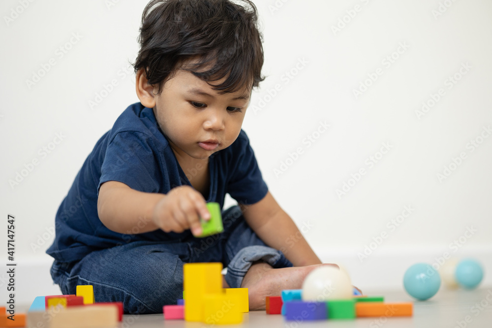 An Asian boy about 1 year old. Playing in the living room in the house He plays wooden toys in different colors. He is wearing a blue shirt. An Asian boy about 1 year old. Playing in the living room in the house He plays wooden toys in different colors. He is wearing a blue shirt.