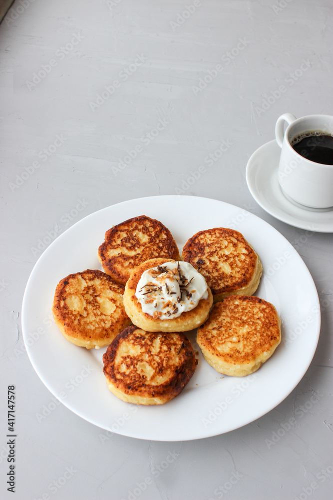 Breakfast of cheesecakes on a plate with sour cream. Breakfast of cheesecakes on a plate with sour cream.