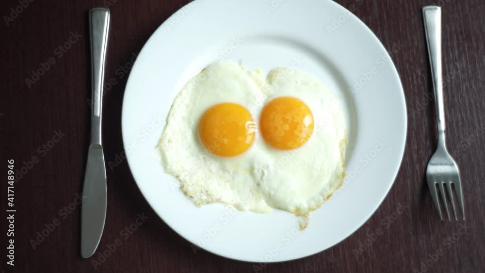 Fried eggs on plate putting plate with fried eggs on wooden table close up white porcelain plate with fried egg traditional breakfast meal serving breakfast breakfast food Fried eggs on plate putting plate with fried eggs on wooden table close up white porcelain plate with fried egg traditional breakfast meal serving breakfast breakfast food