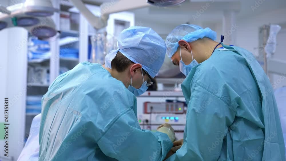 Surgeons work in the operating room. Professional doctors in medical uniform conduct an operation on a leg to a patient in the modern hospital. Surgeons work in the operating room. Professional doctors in medical uniform conduct an operation on a leg to a patient in the modern hospital.