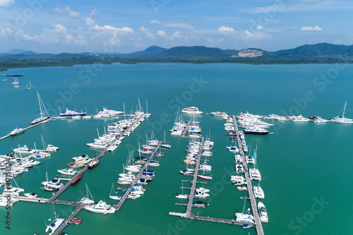 Aerial View Top down Drone shot of Yacht and sailboat parking in marina Transportation and travel background concept Beautiful sea with mountain Blue sky white clouds background