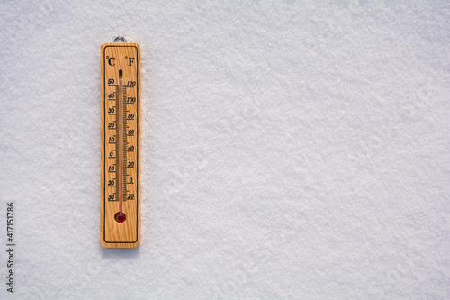Celsius and Fahrenheit thermometer on the surface of white pure snow. Copy space