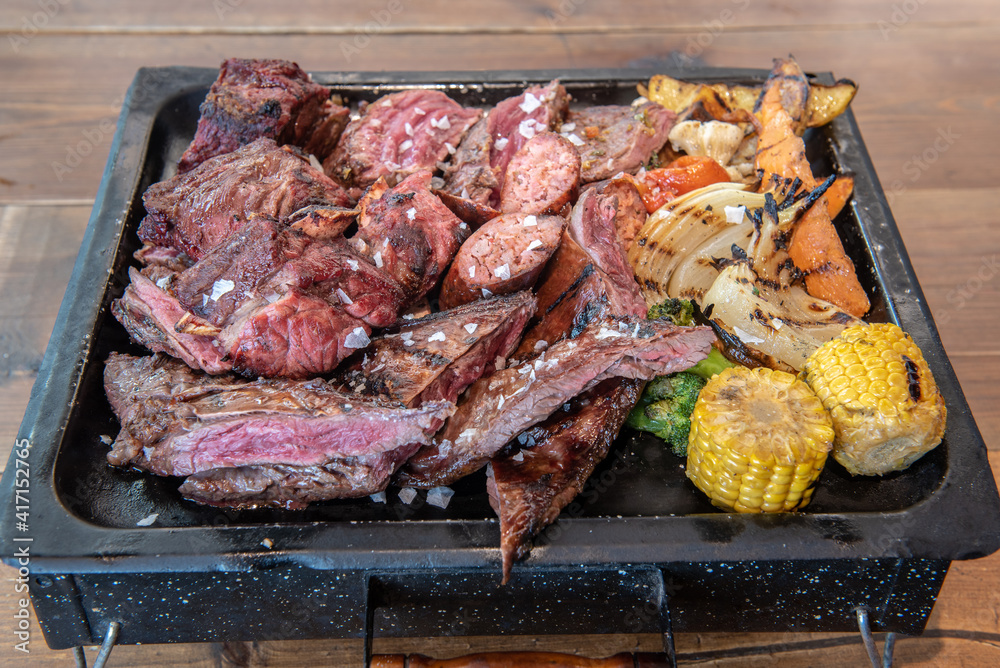 Complete grill of Argentine Asado of meat with vegetables and served in Brasero